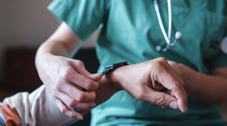 Nurse fitting patient with monitoring technology
